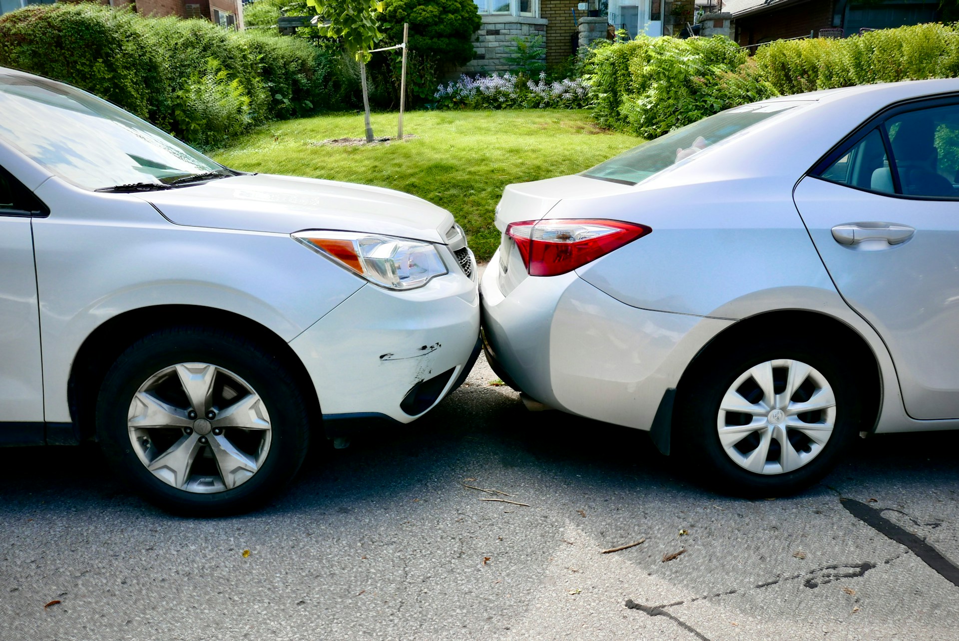 Two cars parked side by side in a driveway, showing no visible damage or signs of an accident.