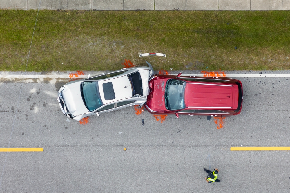 Overhead view of a damaged car on the road, showing significant impact from a collision with another vehicle.
